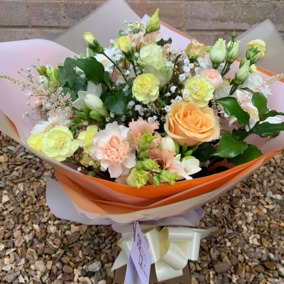Peaches and Creams - A lovely mix of seasonal flowers and foliage in Peach and Cream shades made into a watered hand tied design