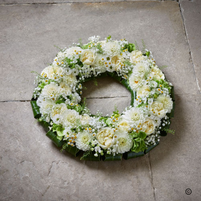 White Loose Wreath OFP19(D) - The purity of this beautiful wreath exudes a calming effect on the saddest of days. The compact nature of this design is highlighted with pretty texture and shiny foliage edging.